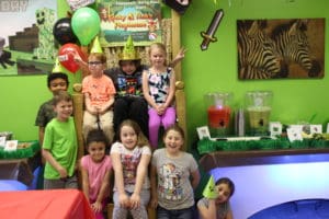 Party-goers sitting on the throne and standing arounf the throne in the Kicky & Tink's party room