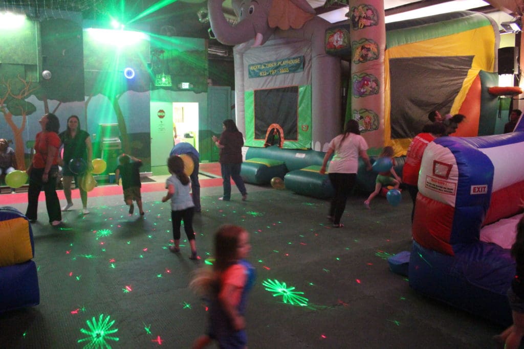 Kids playing in the jungle-themed party room with inflatables, lights, dancing and more